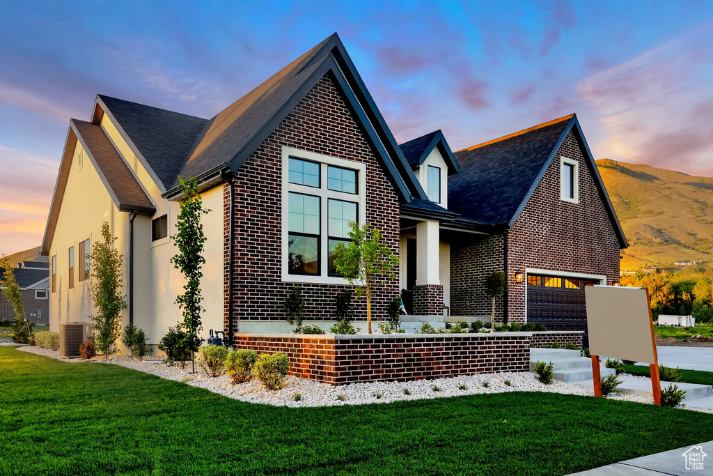 View of front of house featuring brick siding, a front lawn, driveway, and stucco siding