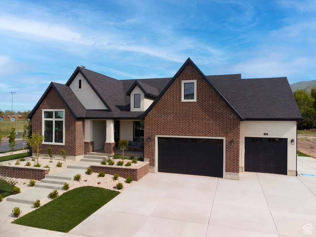 View of front of property with driveway, brick siding, a shingled roof, and an attached garage