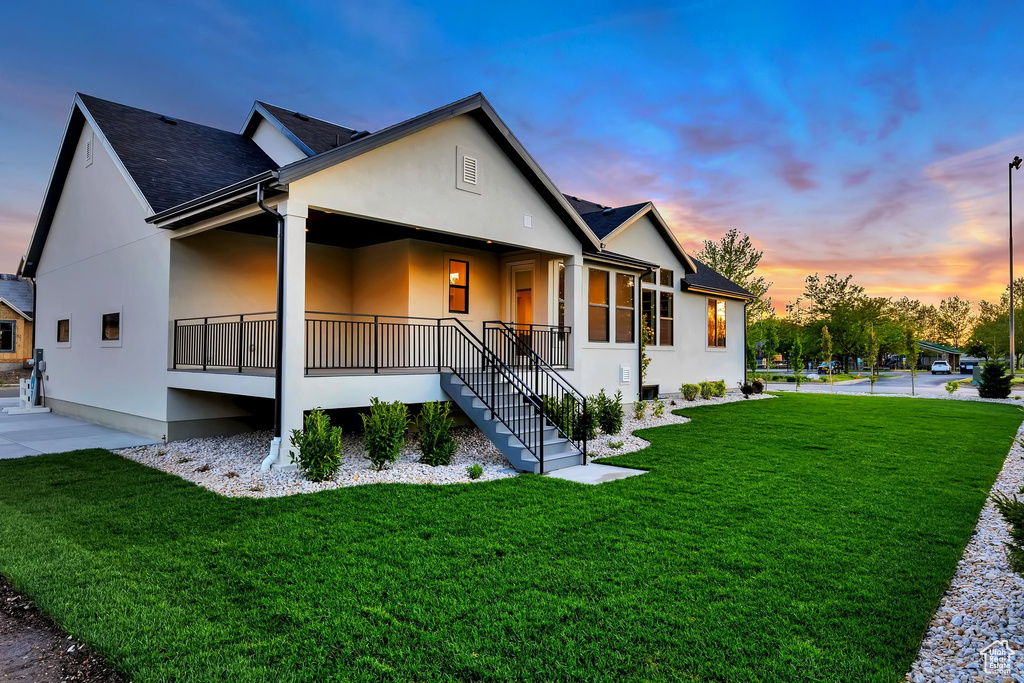 View of front of property featuring stucco siding, a front yard, a porch, and roof with shingles