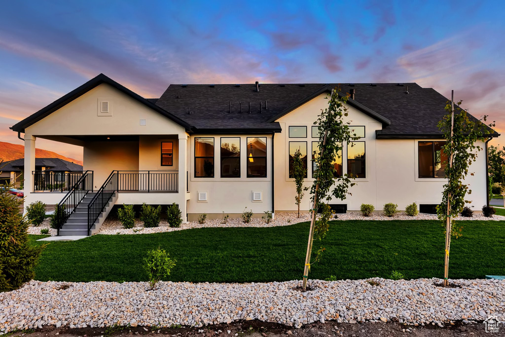 View of front of house featuring stucco siding, a front lawn, a shingled roof, and a porch