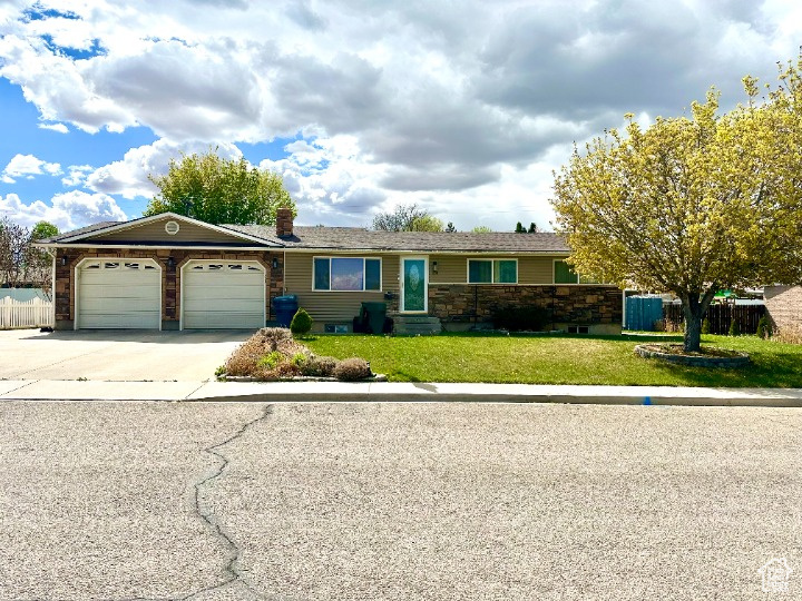 Ranch-style house with driveway, a chimney, fence, a front lawn, and an attached garage