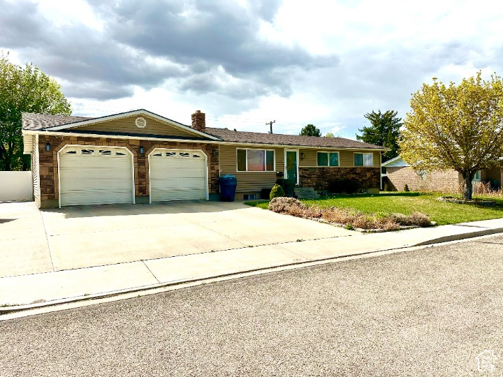 Ranch-style home featuring a garage, a front lawn, a chimney, and concrete driveway