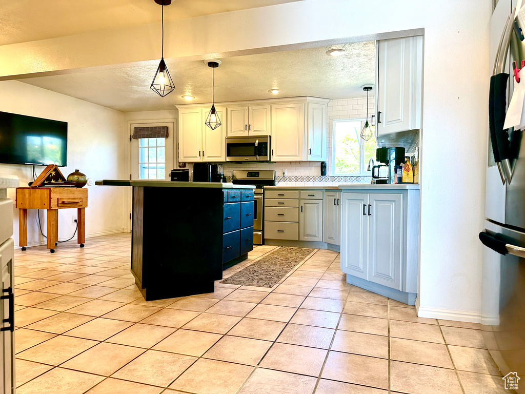 Kitchen featuring appliances with stainless steel finishes, healthy amount of natural light, pendant lighting, and a textured ceiling