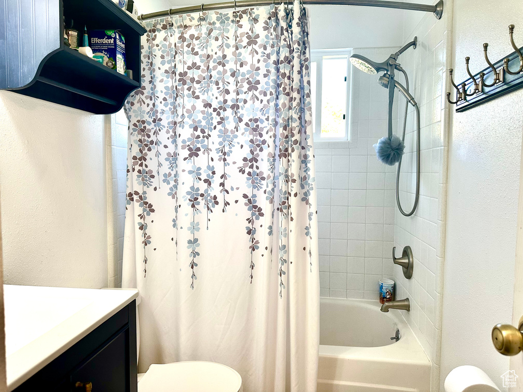 Bathroom featuring vanity, shower / bath combo with shower curtain, toilet, and a textured wall