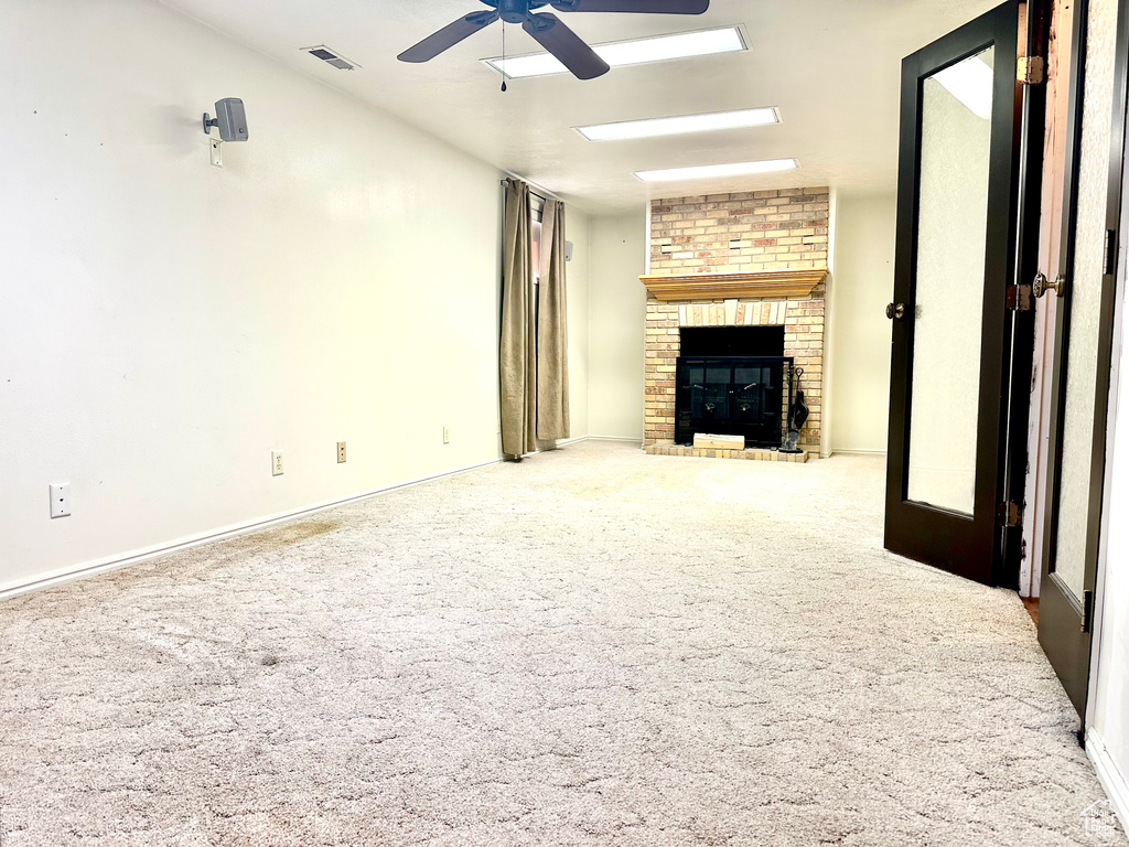 Unfurnished living room featuring ceiling fan, a fireplace, carpet, and baseboards
