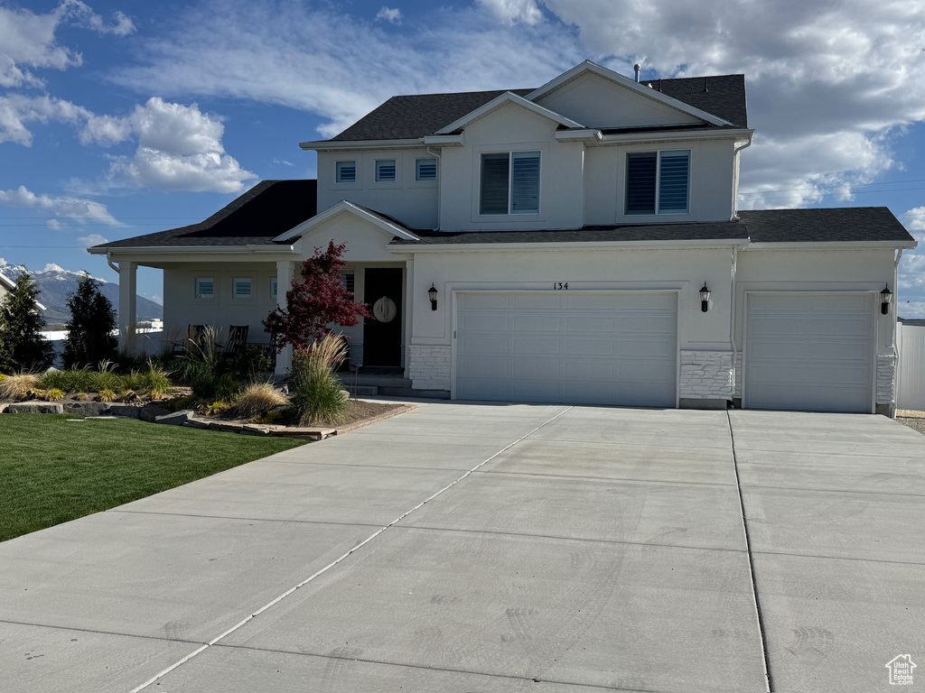 View of front of house featuring a garage, stucco siding, a front lawn, and driveway