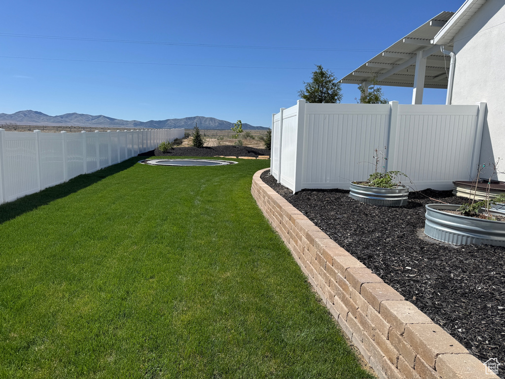 View of yard with a mountain view, a garden, and a fenced backyard