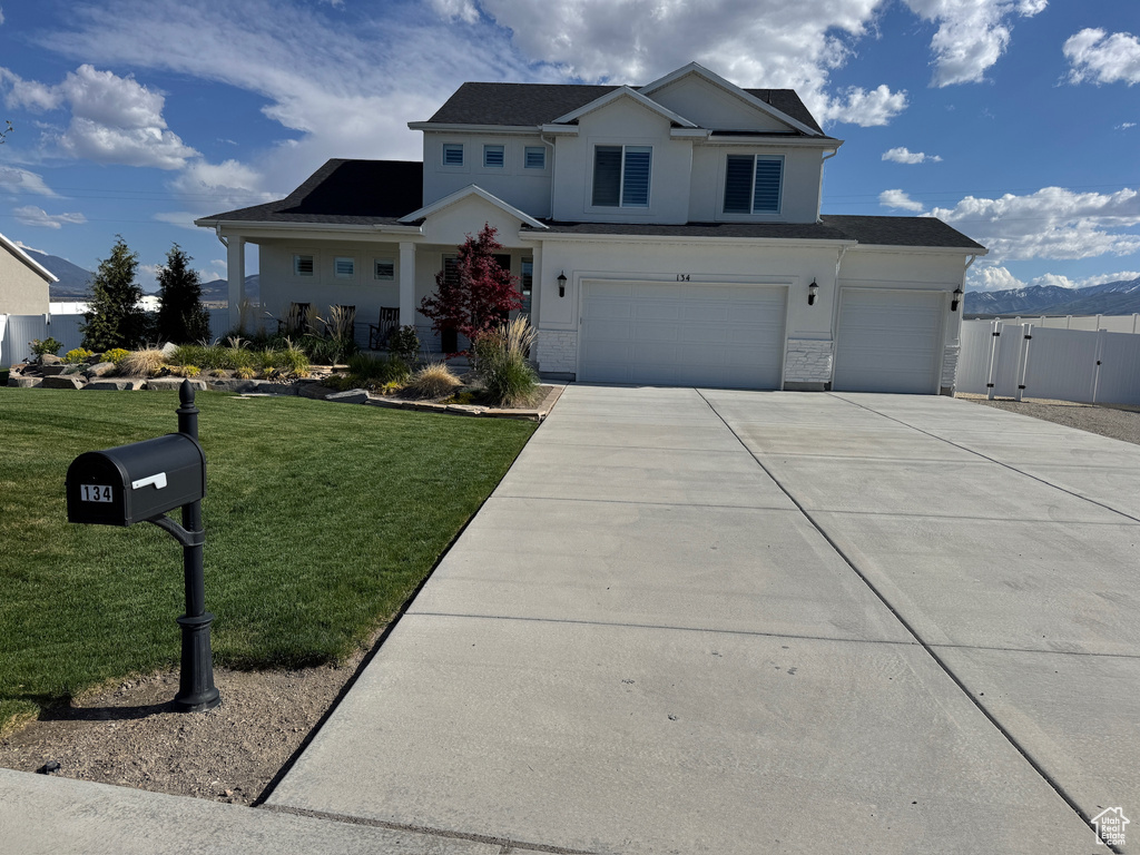 View of front of home with an attached garage, stucco siding, fence, concrete driveway, and a front lawn