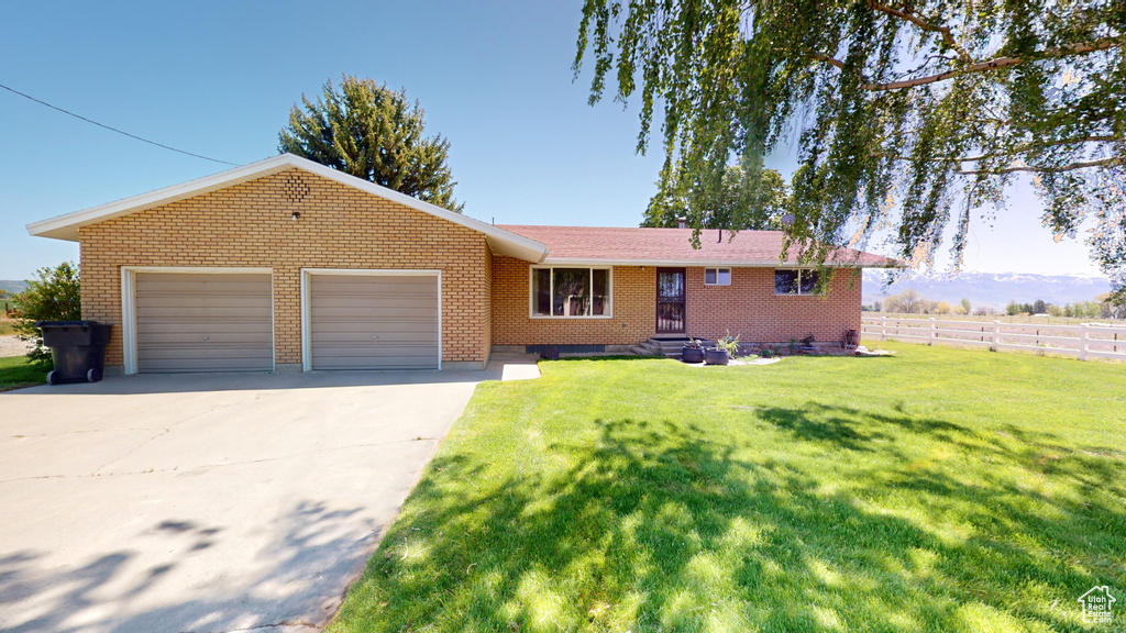 Single story home featuring fence, concrete driveway, an attached garage, a front yard, and brick siding