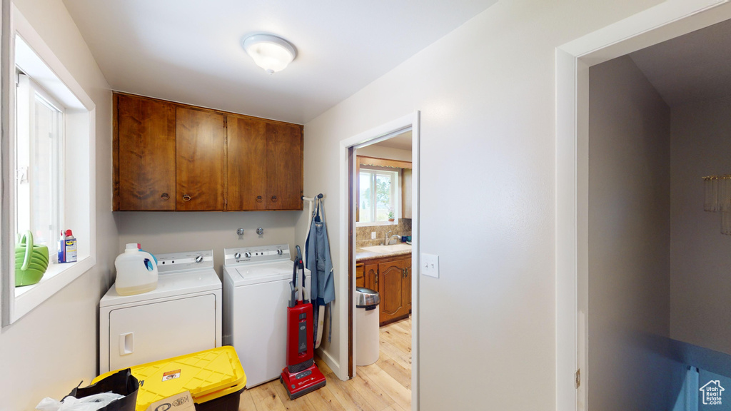 Laundry room featuring a sink, cabinet space, light wood-style floors, and washing machine and clothes dryer