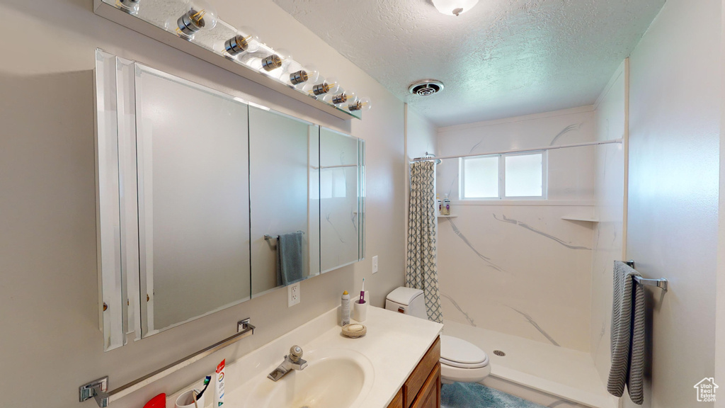 Bathroom featuring visible vents, toilet, a stall shower, a textured ceiling, and vanity