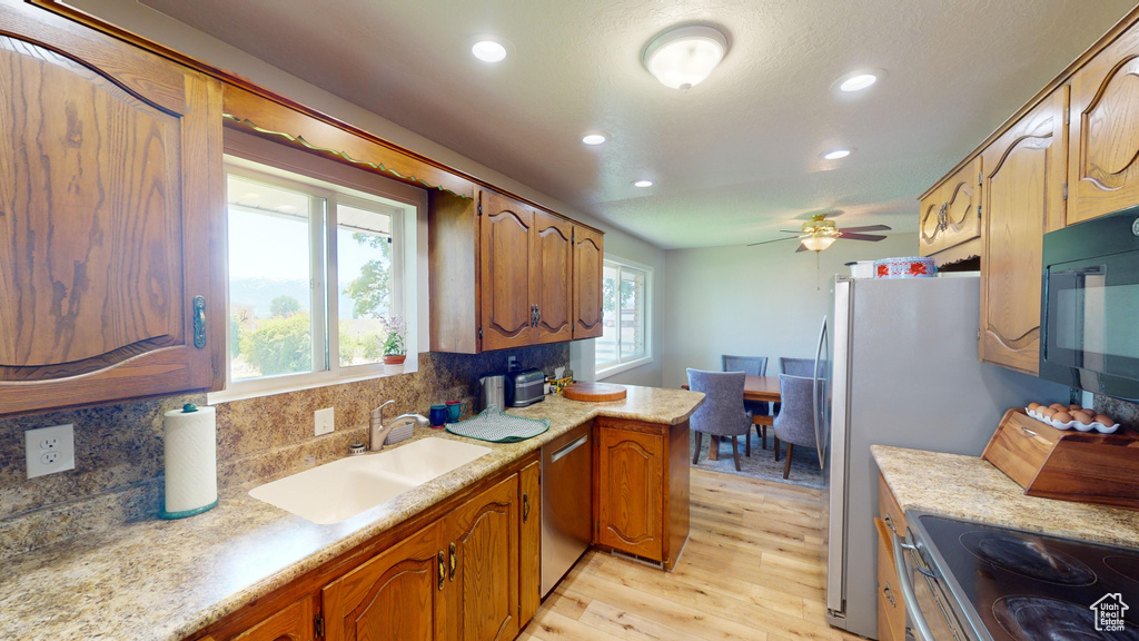 Kitchen featuring light wood-style flooring, a sink, black microwave, light countertops, and dishwasher
