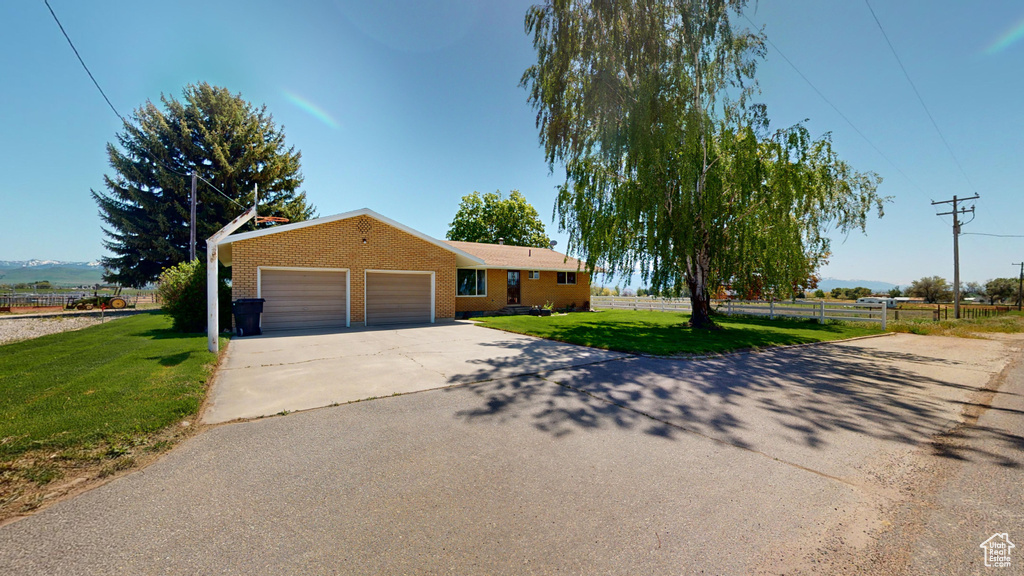Ranch-style home featuring a front yard, fence, an attached garage, concrete driveway, and brick siding