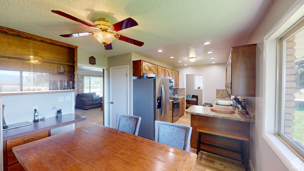 Dining room featuring recessed lighting, light wood-style flooring, a textured ceiling, and ceiling fan