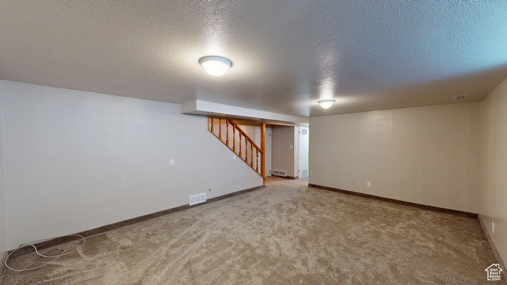 Finished below grade area featuring stairway, carpet flooring, baseboards, and visible vents