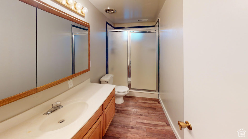 Full bathroom with vanity, wood finished floors, baseboards, an enclosed shower, and toilet