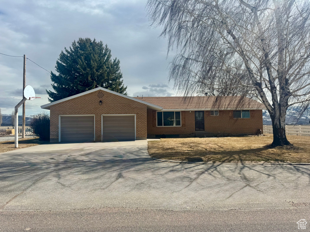 Single story home featuring a garage, brick siding, and driveway