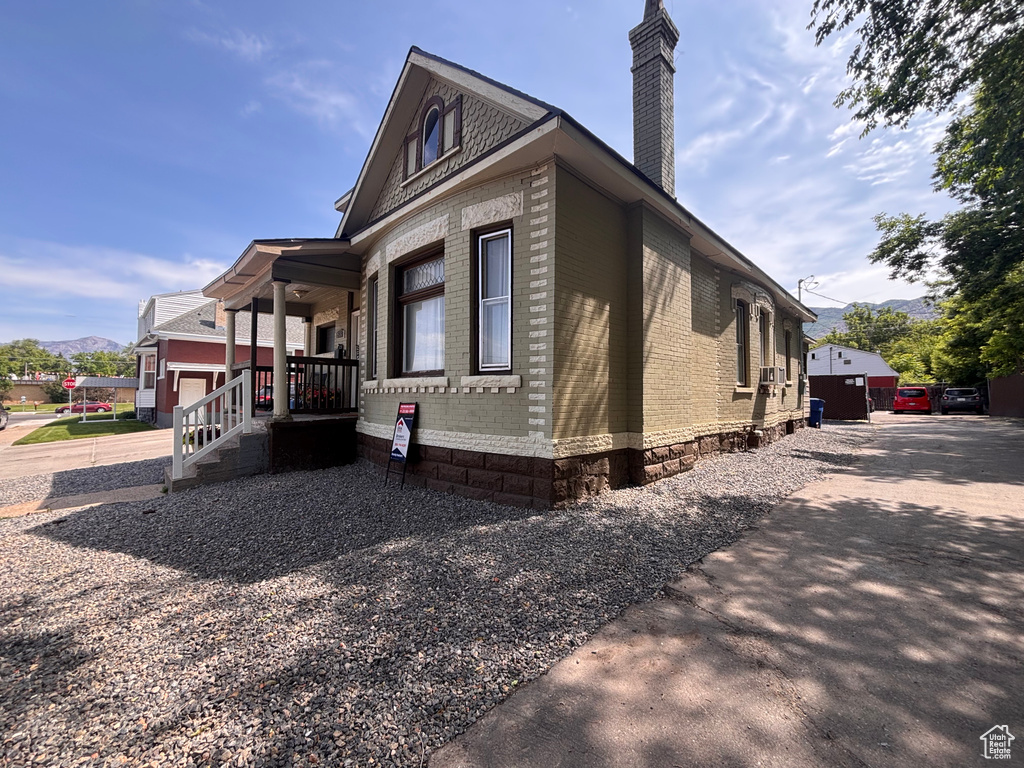 View of side of property featuring a chimney, brick siding, and a mountain view