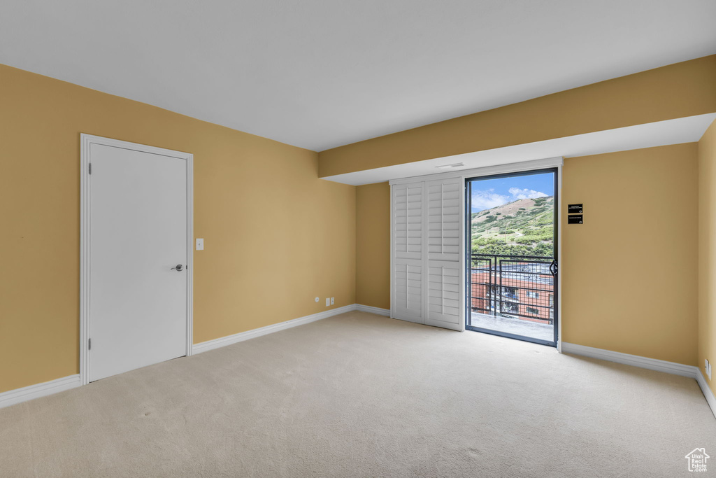 Empty room with light colored carpet and baseboards
