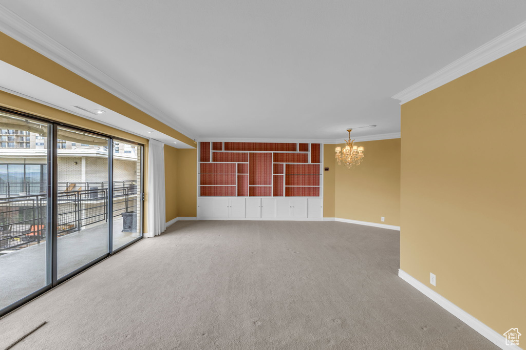 Unfurnished room with a chandelier, crown molding, baseboards, and carpet