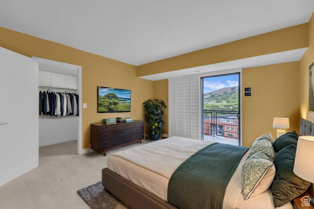 Bedroom featuring a walk in closet, baseboards, light carpet, and a closet