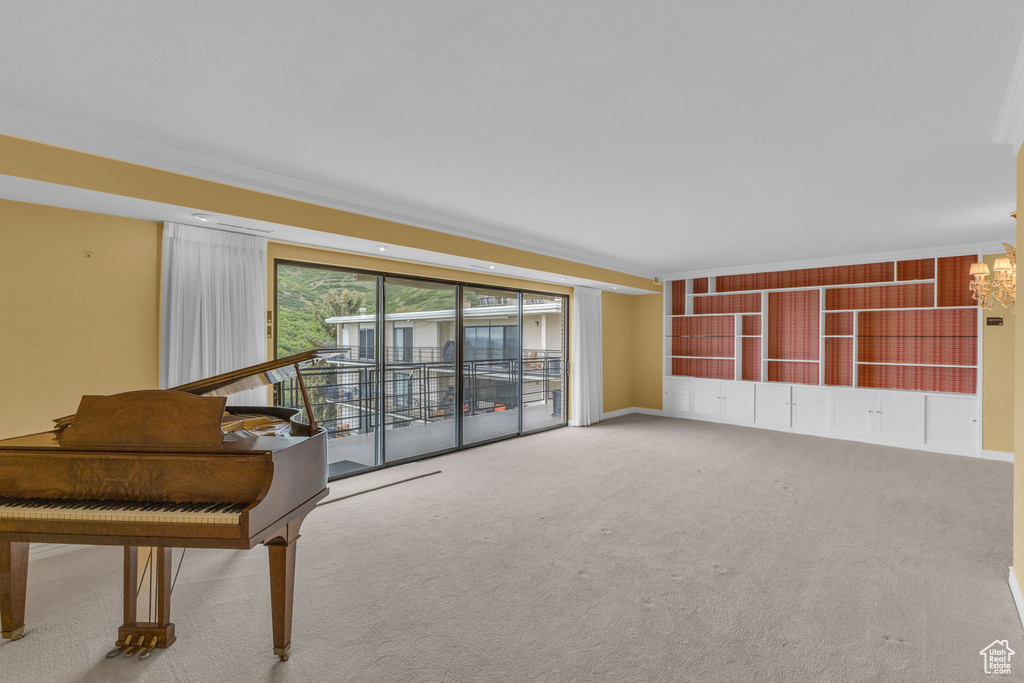 Carpeted living room featuring a chandelier, ornamental molding, and baseboards