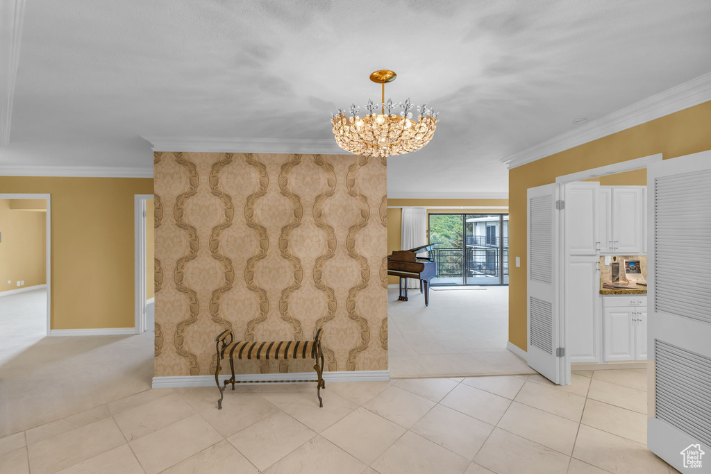 Hall featuring light carpet, a chandelier, baseboards, and ornamental molding