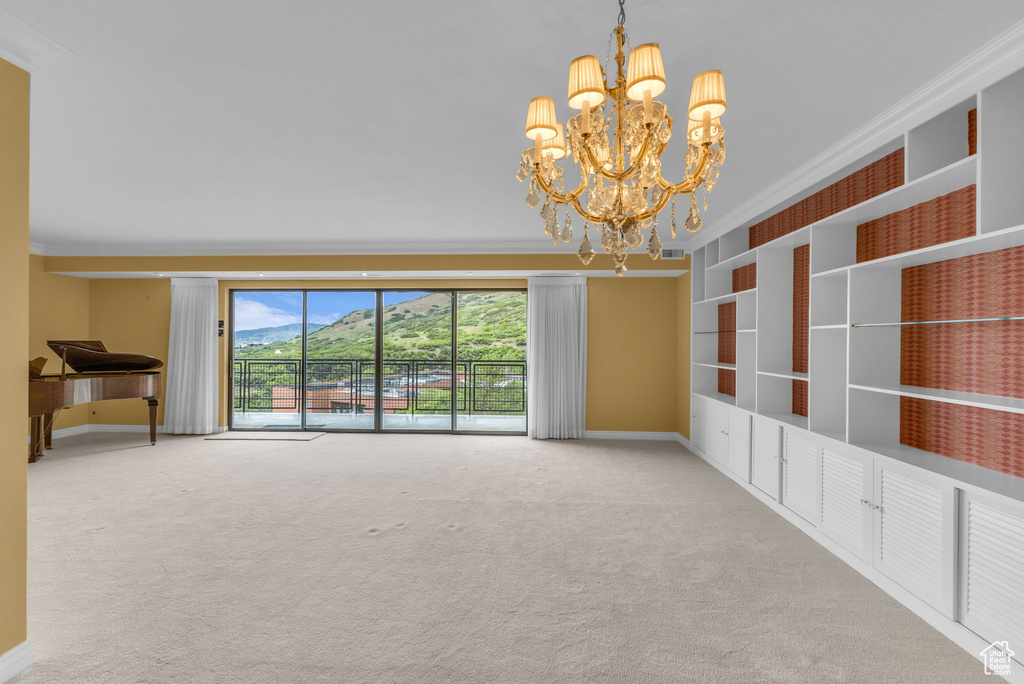 Carpeted spare room featuring a chandelier, ornamental molding, and baseboards