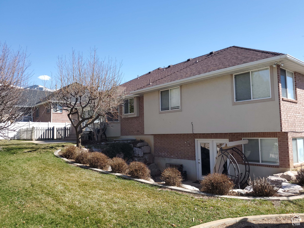 Back of house with fence, brick siding, and a lawn