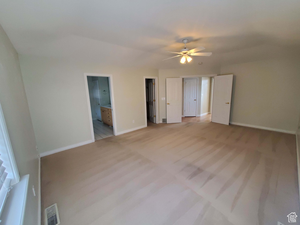 Unfurnished bedroom featuring visible vents, ceiling fan, ensuite bath, and baseboards