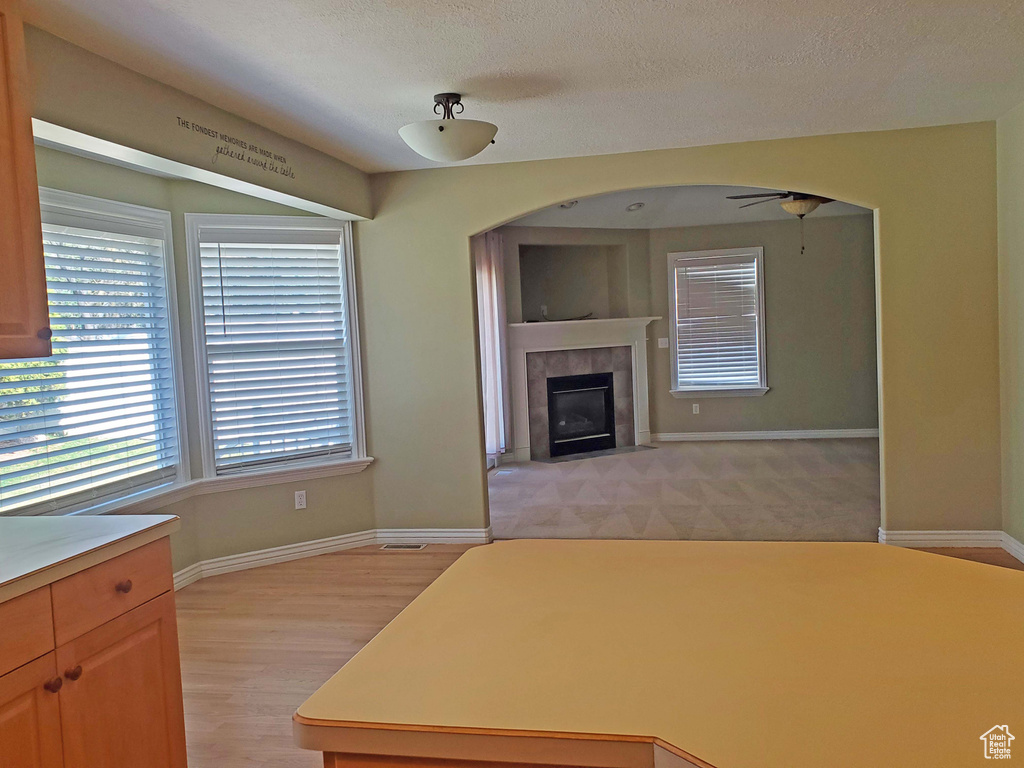 Kitchen with a tiled fireplace, light countertops, baseboards, and ceiling fan
