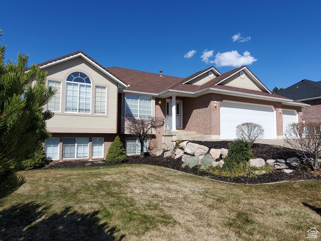 Ranch-style house with brick siding, an attached garage, and a front yard
