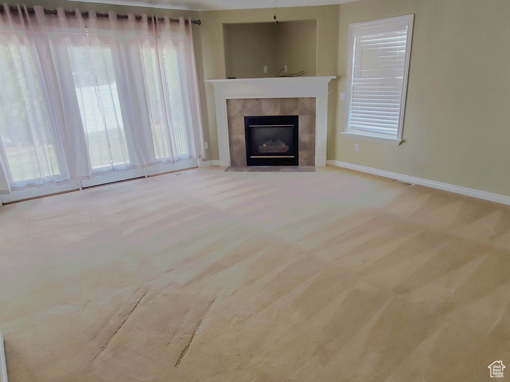 Unfurnished living room with baseboards, carpet floors, and a tile fireplace