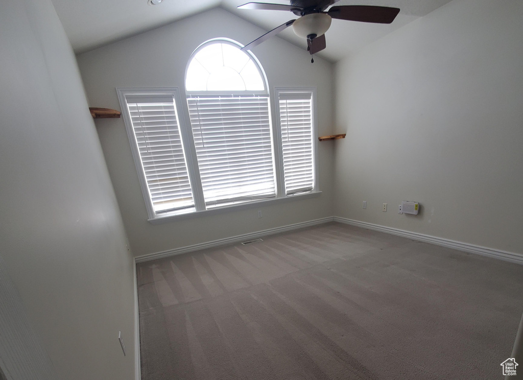 Carpeted spare room with baseboards, ceiling fan, and vaulted ceiling