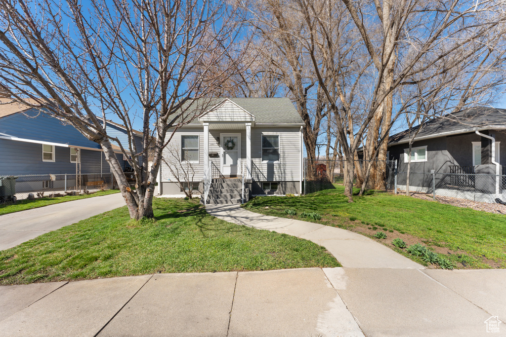 View of front of property with driveway, a front yard, and fence