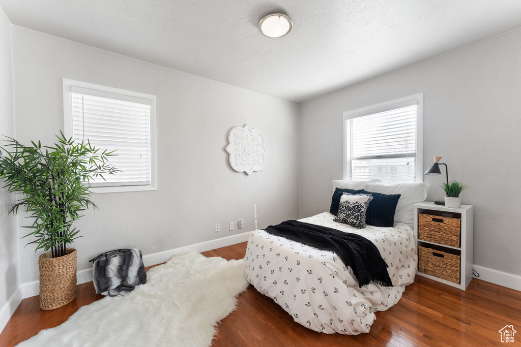 Bedroom featuring multiple windows, baseboards, and wood finished floors