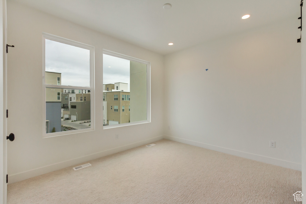 Carpeted empty room featuring visible vents, baseboards, and a wealth of natural light