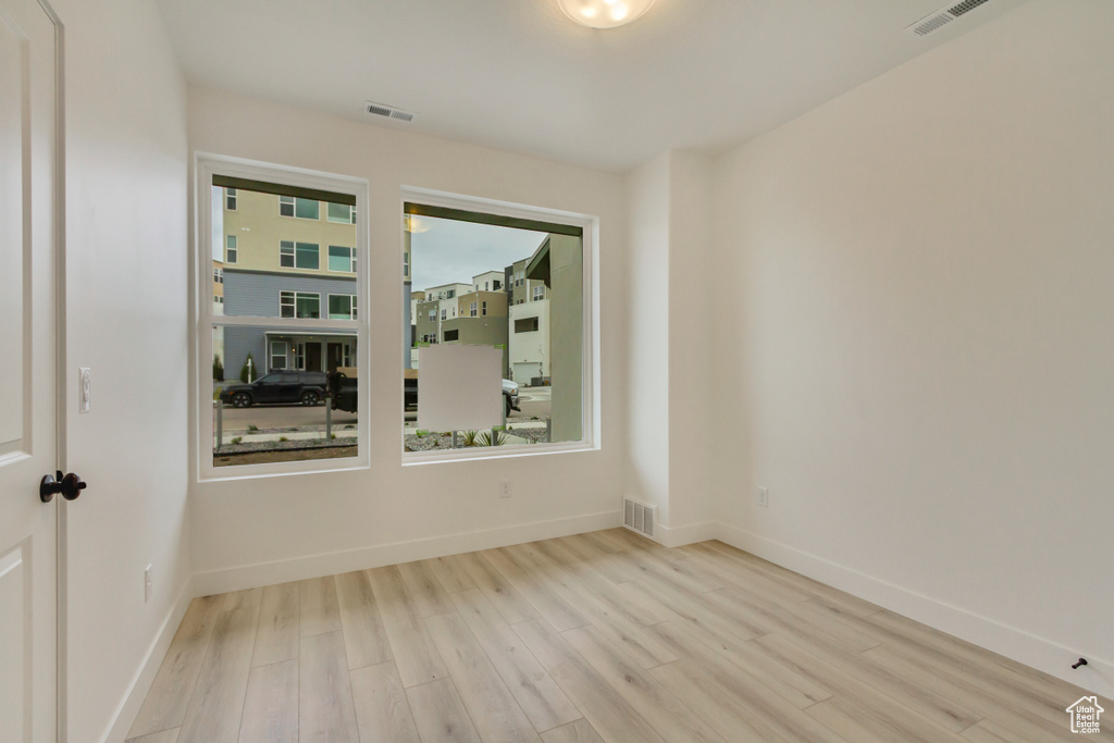 Spare room featuring wood finished floors, visible vents, and baseboards