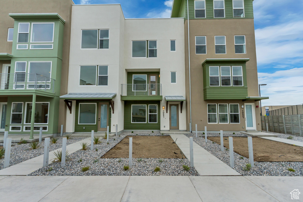 View of property with fence, a standing seam roof, metal roof, and stucco siding