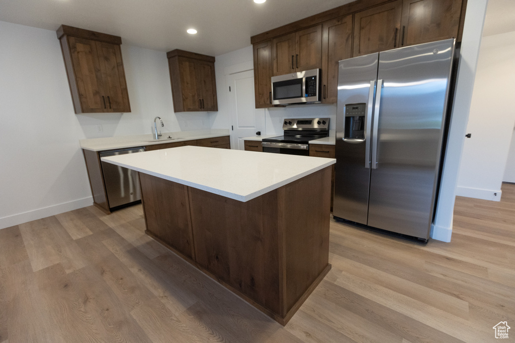 Kitchen featuring light countertops, light wood-type flooring, dark brown cabinetry, and stainless steel appliances