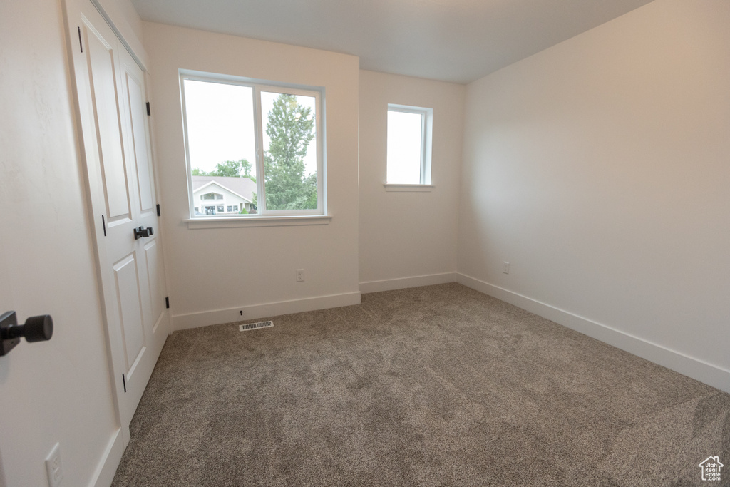 Unfurnished room with baseboards, visible vents, and carpet floors