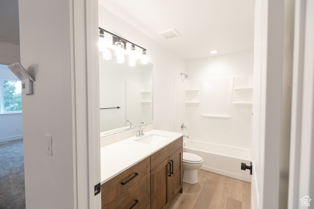 Bathroom with visible vents, toilet, bathing tub / shower combination, wood finished floors, and vanity