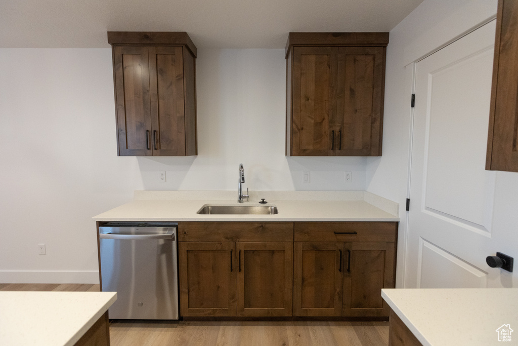 Kitchen with a sink, light wood-type flooring, dishwasher, and light countertops