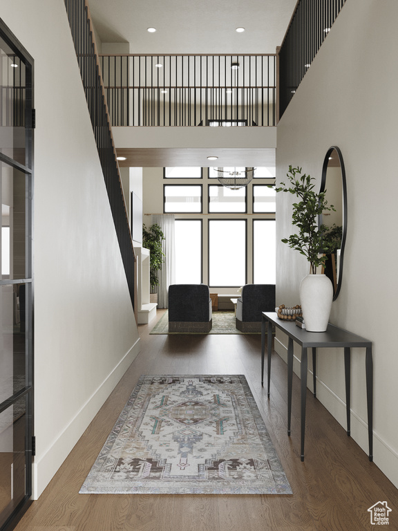 Entryway with a high ceiling, stairs, and wood finished floors