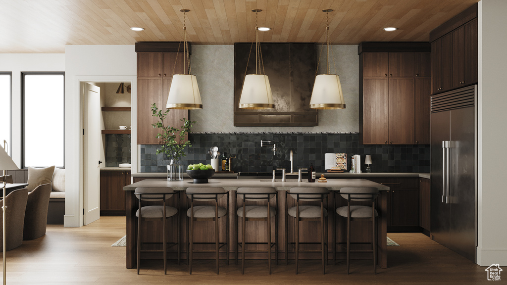 Kitchen featuring high end refrigerator, a center island, light wood finished floors, recessed lighting, and tasteful backsplash