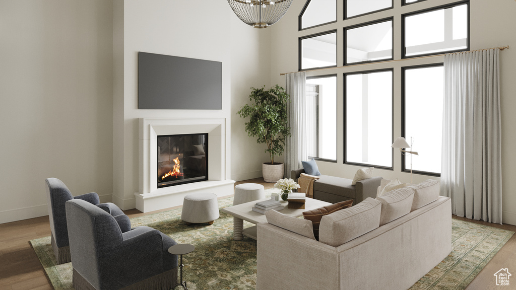 Living area with a glass covered fireplace, light wood-style flooring, and a towering ceiling