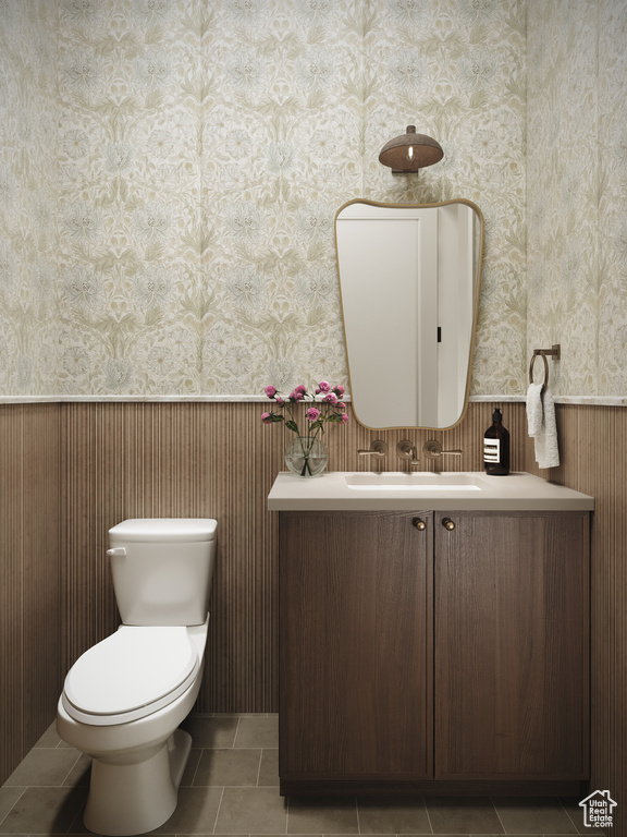 Half bath with wainscoting, vanity, wallpapered walls, and tile patterned floors