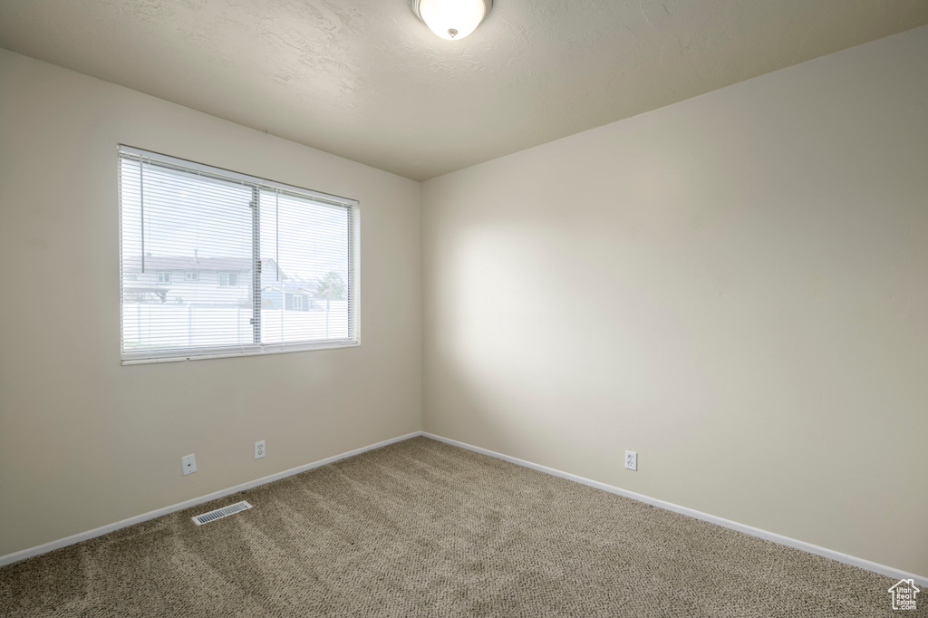 Spare room with visible vents, carpet floors, and baseboards