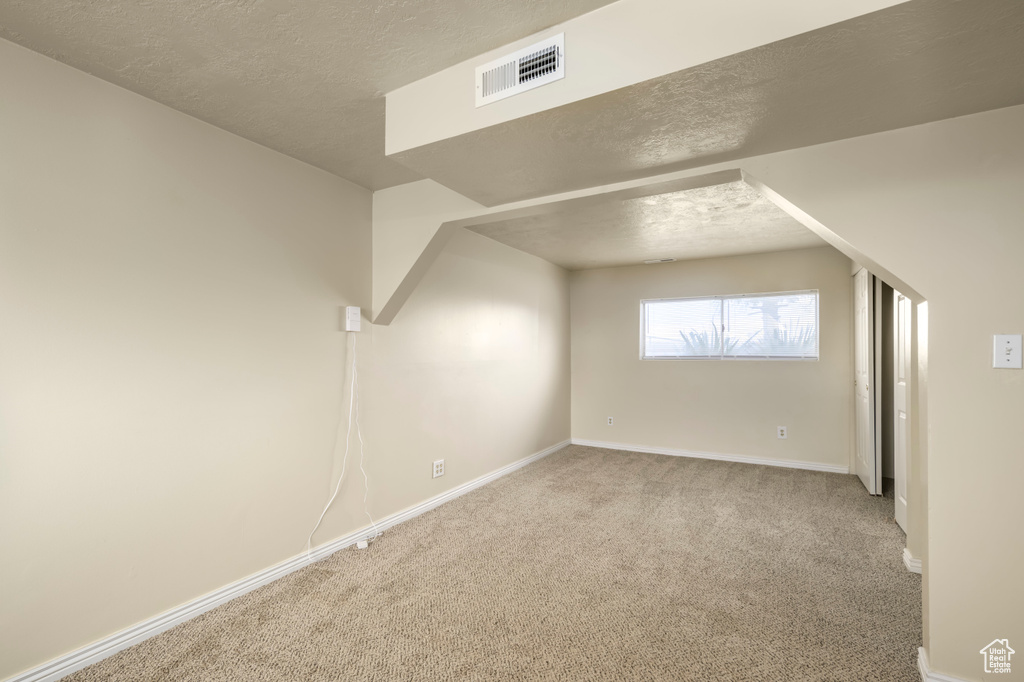 Additional living space with visible vents, baseboards, carpet, and a textured ceiling