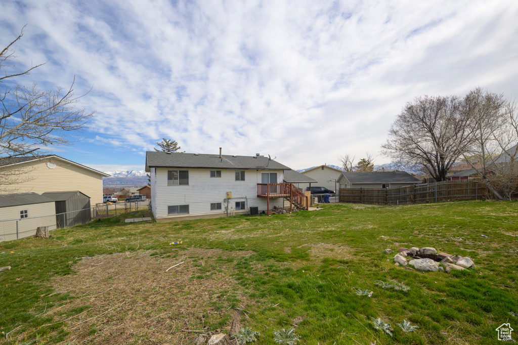Back of house featuring a deck, a yard, and a fenced backyard